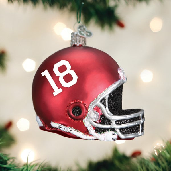 A shiny red football helmet ornament with the number 18 hangs on a Christmas tree, surrounded by green pine needles.