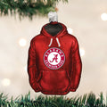 A Christmas tree ornament shaped like a red hoodie with the Alabama Crimson Tide logo hanging from a branch, with blurred white lights in the background.