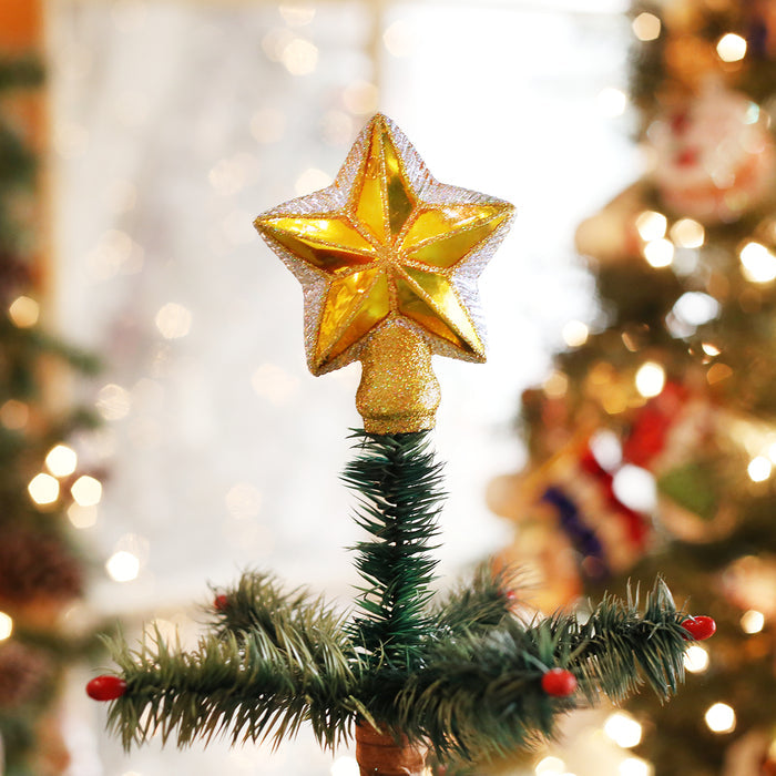 A close-up of a glittery gold star tree topper on a Christmas tree, with blurred lights and ornaments in the festive background.