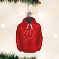A Christmas tree ornament shaped like a red hoodie with a white W logo on the front, hanging from a branch with soft, blurred lights in the background.